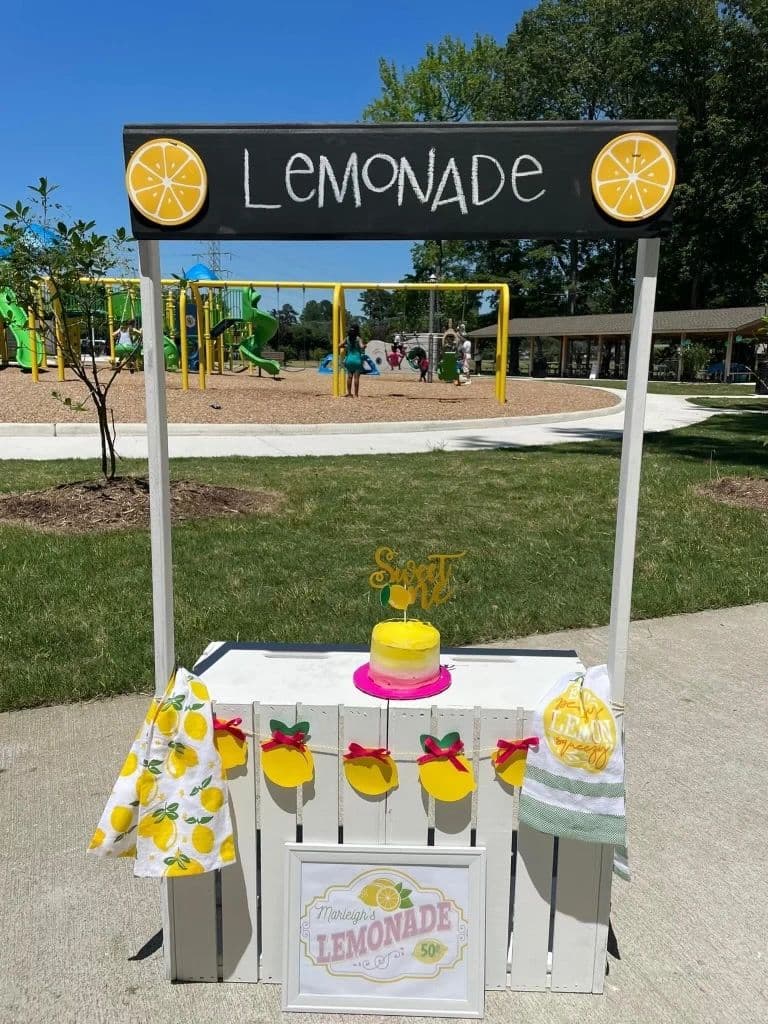 The Child Stand's chalkboard Lemonade sign, lemon garland and yellow cake, close up.